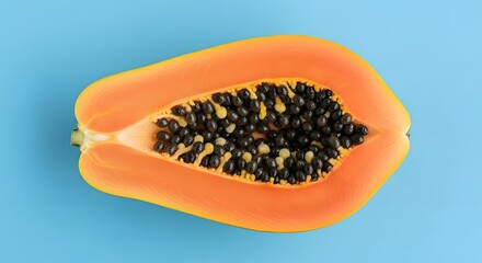 Vibrant papaya half with black seeds on a bright blue background