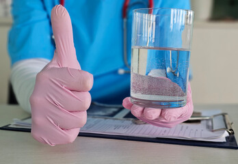 Health professional gives a thumbs up while holding a glass of clean water in a clinical