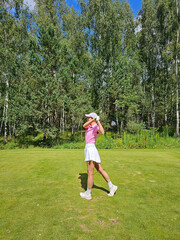 Golf player swings club on a sunny day in a forested area near the green concept