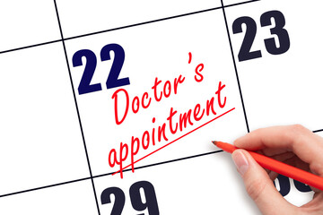 22 nd day of the month. Hand writing Doctor's appointment reminder and drawing a line on calendar with red pen on white background. Health care concept. Planning and scheduling