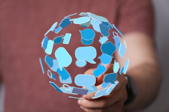 Man holding a globe of blue speech bubbles representing global communication, connection, and digital interaction. Social media and online messa