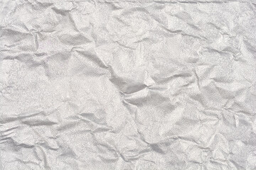 A full-frame, close-up abstract background of heavily crumpled and textured silver metallic foil with numerous folds and wrinkles