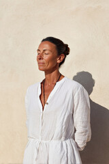 woman with closed eyes and clenched fists radiates joy and relaxation against clean solid background