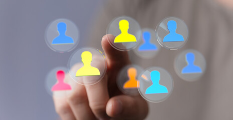 Hand pointing at colorful silhouette icons in a modern tech interface. Representing teamwork, connections and the digital world.