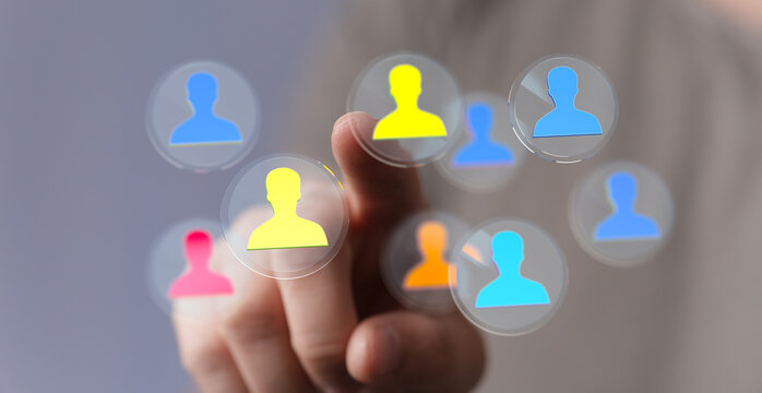 Hand pointing at colorful silhouette icons in a modern tech interface. Representing teamwork, connections and the digital world.