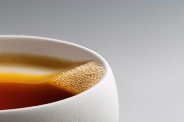 closeup view of droplet of coffee resting on edge of pristine white cup light beautifully