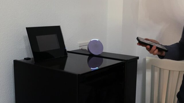 person controls smart wireless device with cell phone at home