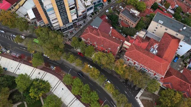 Aerial top-down video of Tirana, Albania, Elbasani road, autumn trees, and surrounding urban architecture.