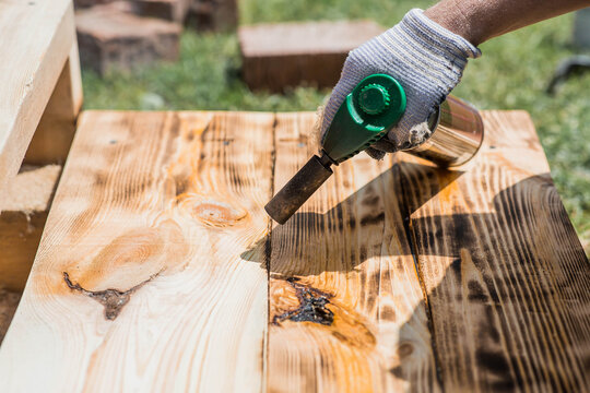 The texture of wood treated with fire using a burner. The process of burning wooden boards. Close-up.