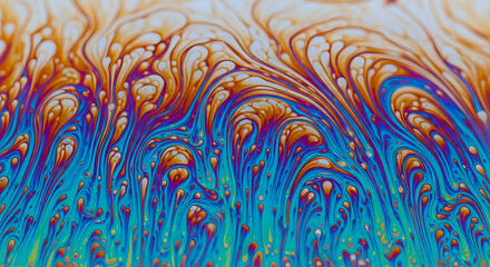 Macro close-up of an iridescent soap bubble film, showing vibrant, flowing, rainbow-like patterns of blue, orange, and red, symbolizing chemistry, abstract flow, and vibrant design