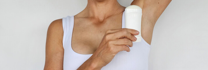 Woman applying deodorant while wearing a white crop top