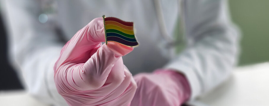 Medical professional holding a rainbow flag pin in a healthcare environment, promoting diversity and inclusion concept