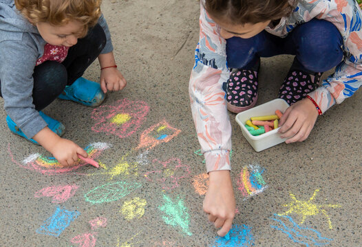 Children draw with chalk on the pavement. Selective focus. - Powered by Adobe