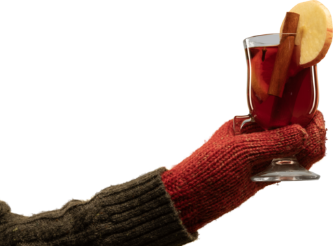 Hand in red winter gloves holding mulled wine glass with apple slice and cinnamon on transparent background. Concept of cozy seasonal lifestyle, holiday marketing, and drink advertising.