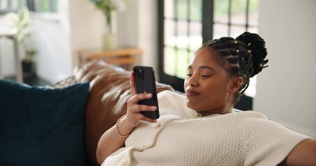 Black woman, phone and relax on sofa, texting and scroll with contact, web chat or notification in home. African person, smartphone and click on mobile app, smile and post on social media at house - Powered by Adobe