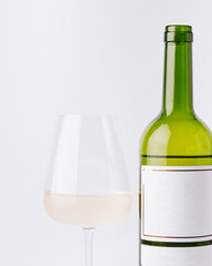 Enjoying a glass of white wine next to a bottle on a white background