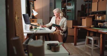 Woman, pointing and tablet for ecommerce in warehouse for logistics, supply chain and catalog. Mature person, writing and digital to confirm orders, track inventory and stock management for delivery - Powered by Adobe