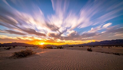 Desert landscape at sunset with radiant sunbeams and streaking clouds, sand dunes in the foreground