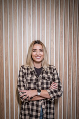 Fototapeta premium Confident young woman smiling standing against wood wall