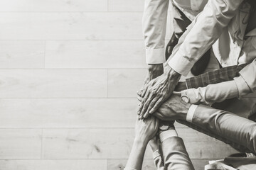 People holding hands together, top view with space for text. Black and white toning. Unity concept