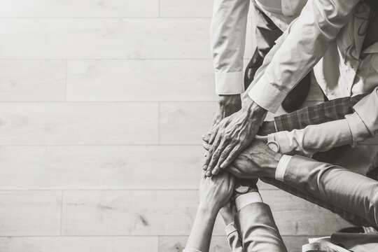 People holding hands together, top view with space for text. Black and white toning. Unity concept