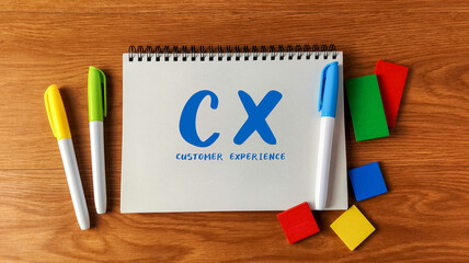 Customer Experience (CX) concept written on a notebook with colorful markers and blocks on a wooden...