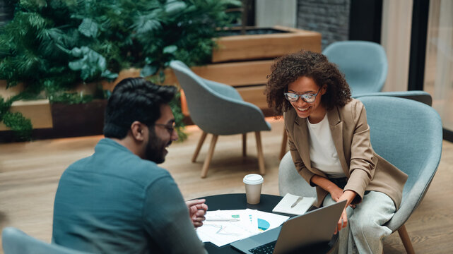 two colleagues analyzing documents at table, cross-referencing charts and metrics while developing strategy