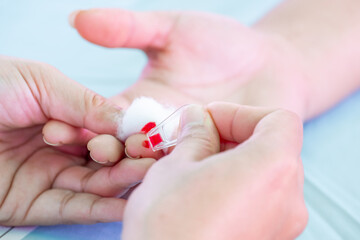 Close up of a healthcare professional using a lancet to prick a patient’s fingertip for a blood test. Medical procedure for glucose check, diabetes test, or health examination in clinic.