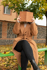 Woman covering her face with a notebook