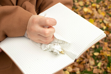 A woman's hand tears a page out of a notebook