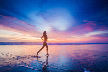 a girl runs into the sea at sunset