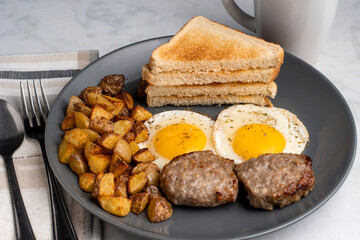 fried eggs served with breakfast sausage patties and home fries