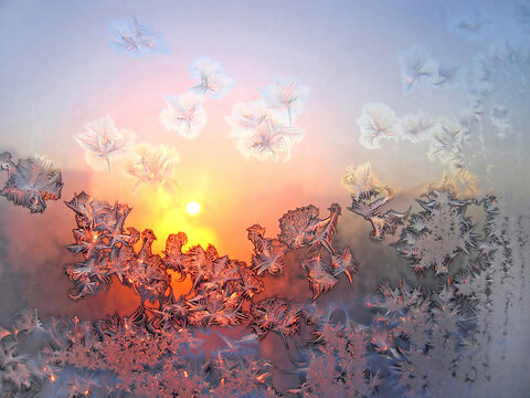 Beautiful natural ice patterns and sunlight on winter window glass, close-up