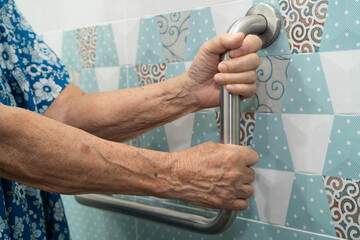 Asian elderly woman use safety handrail in bathroom.
