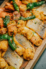 A plate of food with a variety of meats and vegetables, including fish, shrimp, and peppers