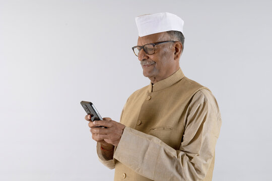 Indian senior male politician using smartphone on studio background