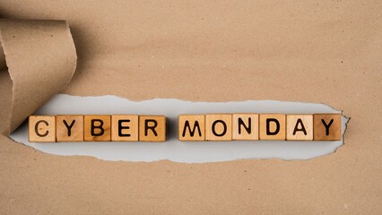 Wooden letter blocks spelling cyber monday on a torn paper background with a ribbon representing online shopping and sales events