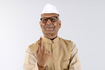 Indian senior politician showing vote finger index 
against studio background