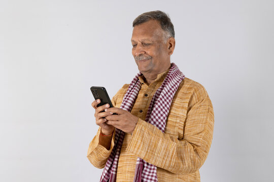 Indian rural old man using mobile at studio background - elder villager using phone - Concept of senior rural people using technology and smartphone