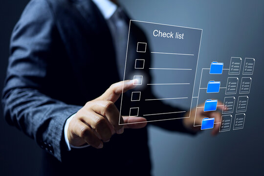 document checklist concept with businessman pointing on virtual interface to tick on done item that opens from storage folder