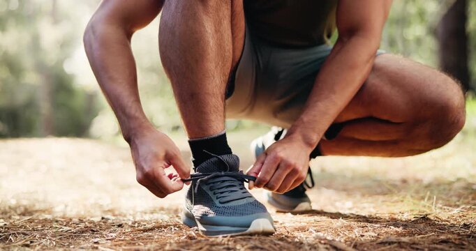Man, hands and tying with shoes in forest for hiking, fitness preparation or outdoor run in nature. Closeup, male person or runner getting ready with tie, sneaker or laces for trekking or exercise