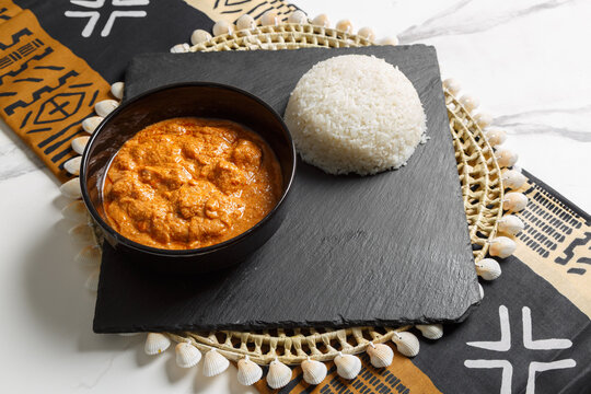 Maf&eacute; &agrave; la viande servie avec riz blanc, pr&eacute;sent&eacute; sur une ardoise et un set de table tiss&eacute; africain &ndash; plat traditionnel africain. Cuisine s&eacute;n&eacute;galaise. 