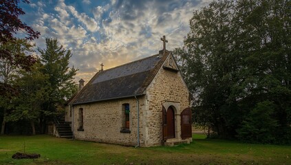 Fototapeta premium Stone Building in a Verdant Setting, Under an Expressive Sky with Drifting Clouds.