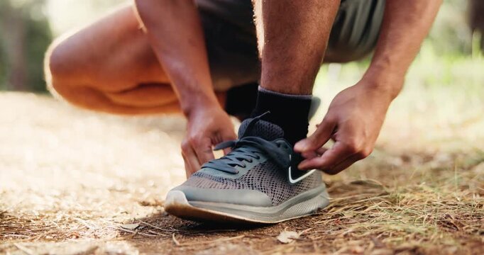 Man, hands and tying with shoes in nature for hiking, fitness preparation or outdoor run in forest. Closeup, male person or runner getting ready with tie, sneaker or laces for trekking or exercise
