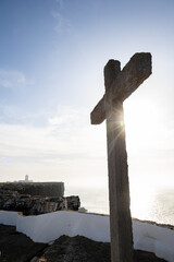 Stone Cross Silhouetted Against Sunrise at Cabo Carvoeiro Cliffside Overlooking the Atlantic Ocean in Portugal