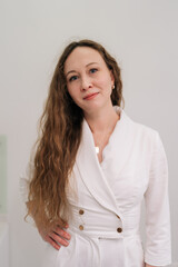 Obraz premium Professional cosmetologist wearing white uniform smiling looking at camera, symbolizing beauty, skincare, and expert aesthetic services offered in modern clinic salon. Concept of beauty treatment.