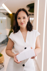 Professional female cosmetologist presenting blank cosmetic product boxes, symbolizing expertise...