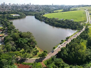 Fototapeta premium Aerial View of a Lake and Urban Area Surrounded by Green Fields and Trees. Concept of urban nature, sustainability, and environmental balance.