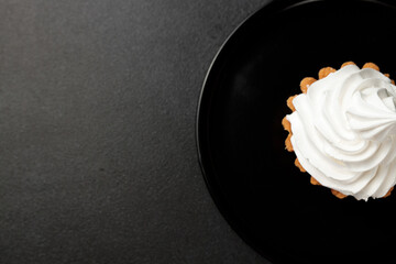 cake basket with protein cream in a black round plate on a black background