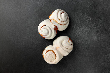 Fragrant Cinnabons with cream on a gray background